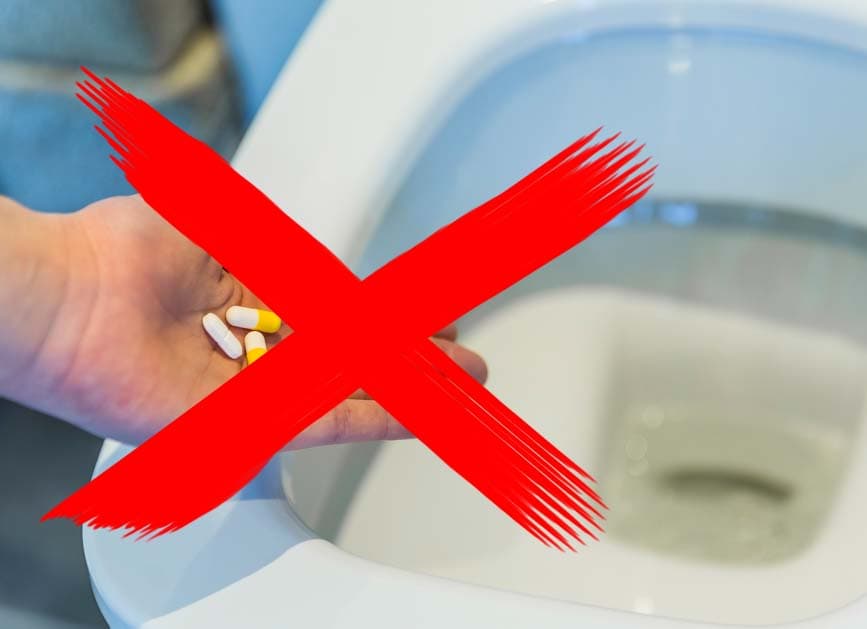 Rotes Kreuz gemalt über Bild mit einer Hand, die Pillen über offene Toilette hält.