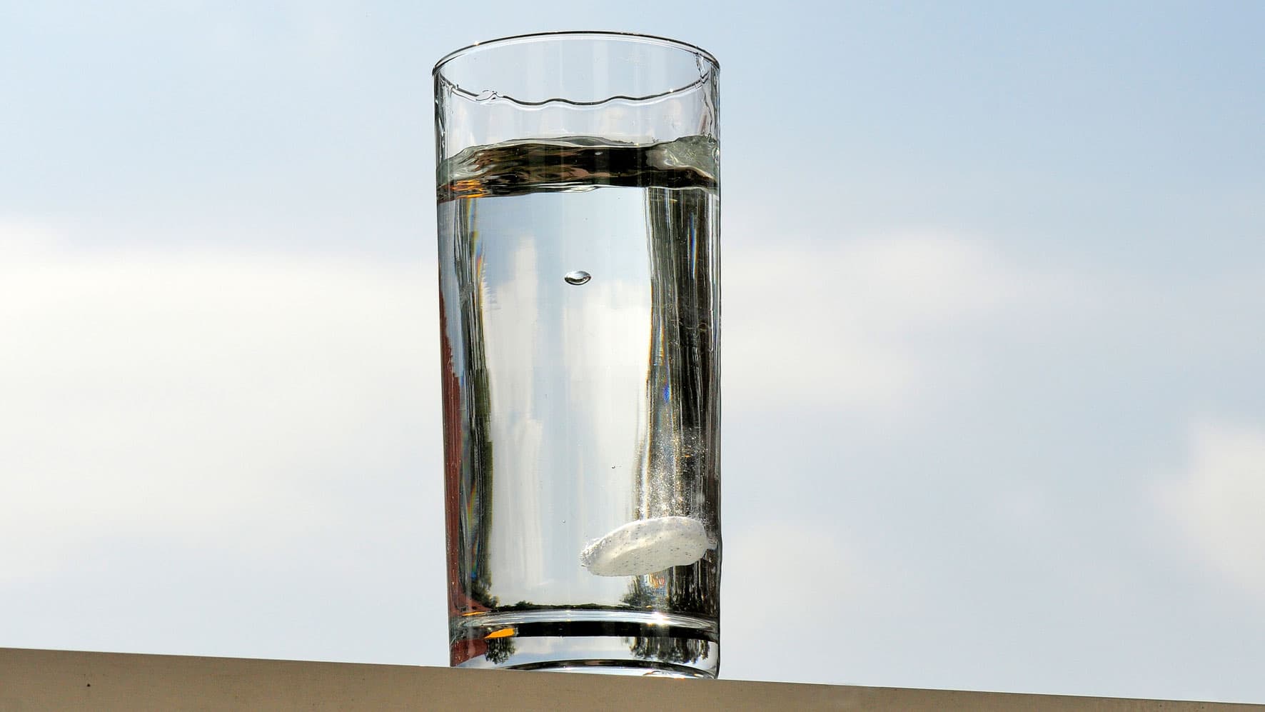 Eine Aspirin-Tablette löst sich in einem Glas Wasser auf.