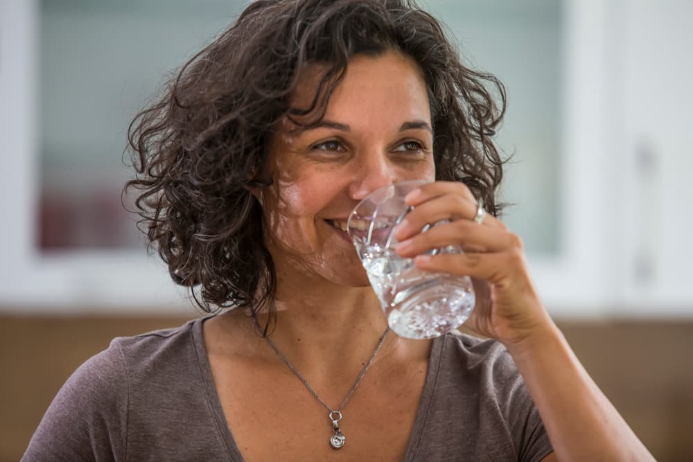 Frau trinkt ein Gas Trinkwasser.